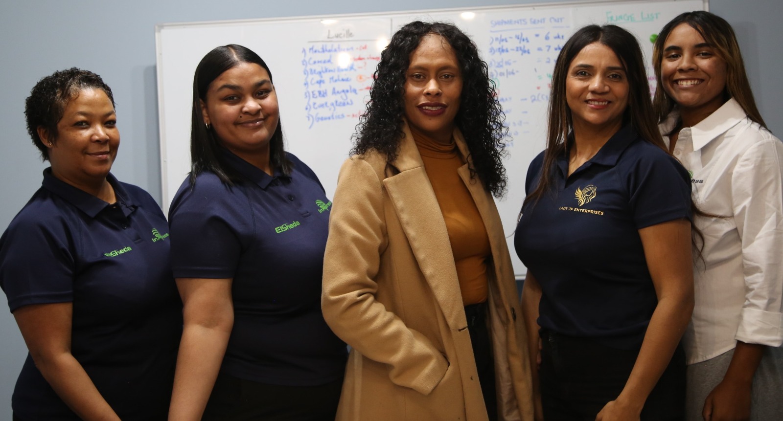 Women entrepreneurs from Her Legacy Consulting's client community standing together in their business premises